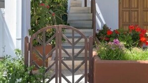 Un edificio blanco con un portón de madera, una escalera y una puerta de madera.