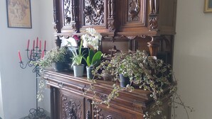 A wooden cabinet with ornate carvings, a candelabra, and various potted plants. - Apartment 'La Vista Sul Castello' with Mountain View, Wi-Fi and Air Conditioning (Compiano)