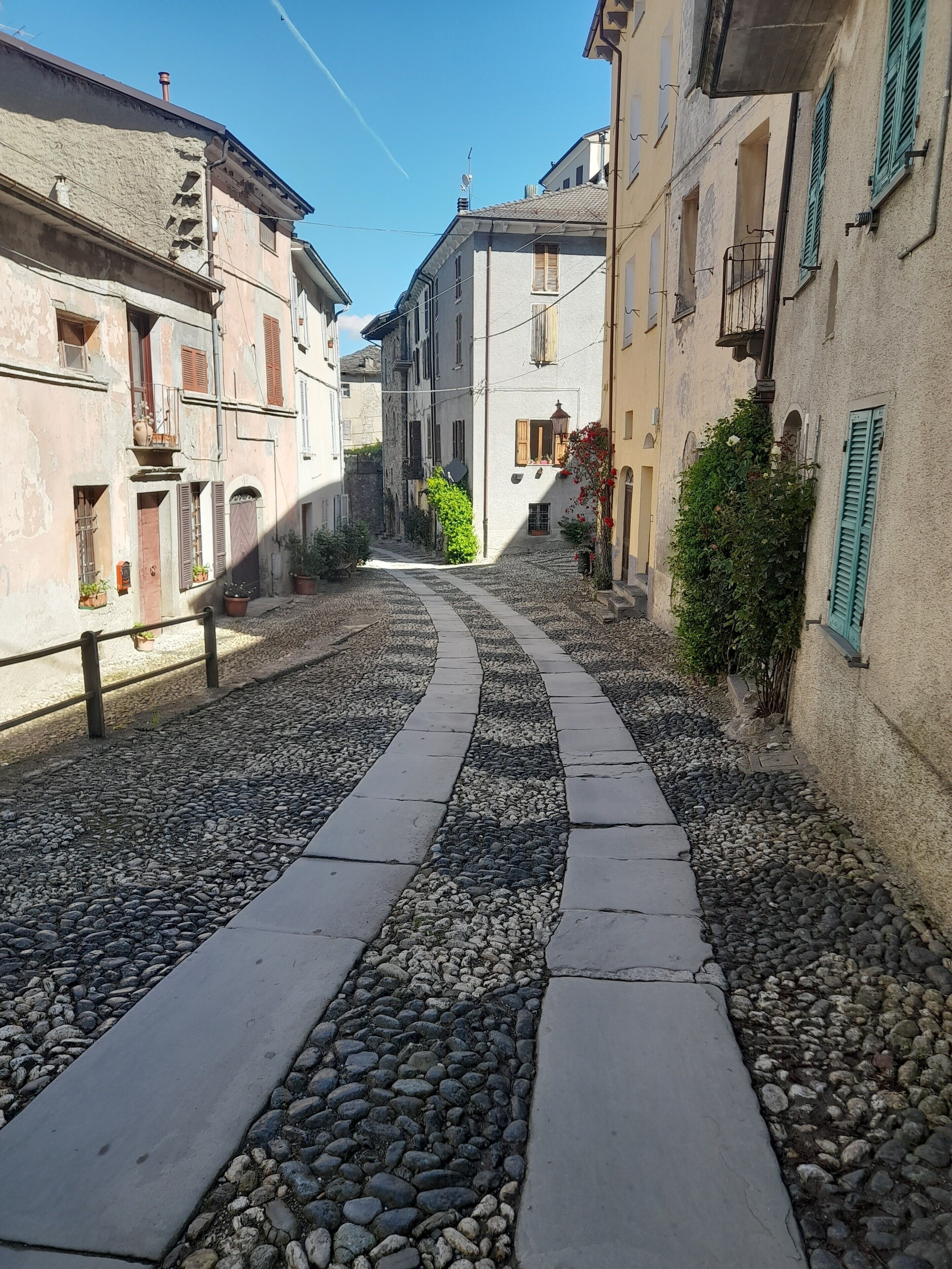 Una stretta strada acciottolata costeggiata da edifici con balconi e persiane.