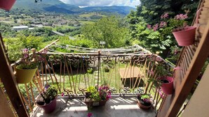 A balcony with a view of a valley, potted plants, and a trellis structure. - Apartment 'La Vista Sul Castello' with Mountain View, Wi-Fi and Air Conditioning (Compiano)