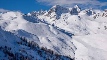 A snow-covered mountain landscape with ski slopes and a clear sky.