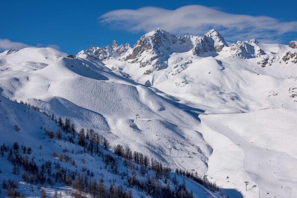 A snow-covered mountain landscape with ski slopes and a clear sky.