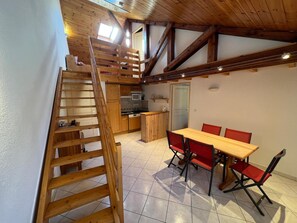 A wooden interior with a dining area, kitchen, and a wooden staircase.