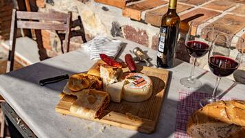 Et bord med en osteanretning, brød, en flaske vin og vinglas.