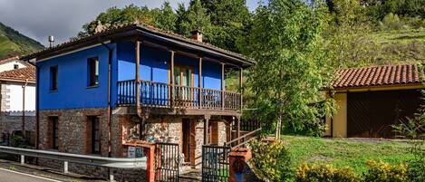 Un immeuble de deux étages doté d’un balcon, d’une façade en pierre et d’un portail en métal.