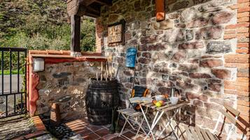 A rustic stone wall with a wooden barrel, a table with a book, and a chair.