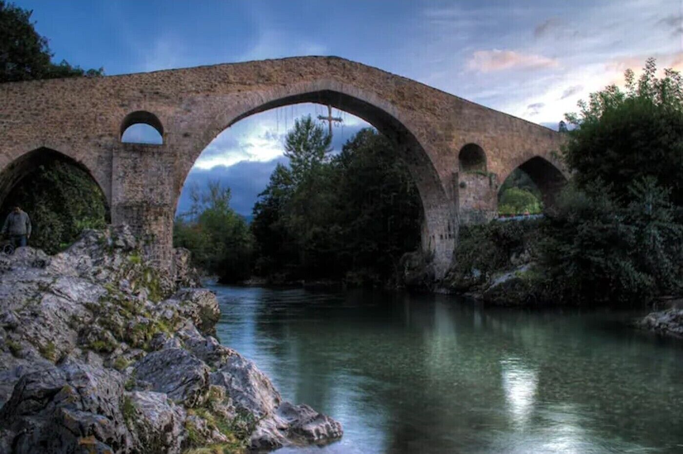 Un ponte in pietra sopra un fiume, con un paesaggio naturale.
