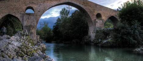 Un puente de piedra sobre un río, con un paisaje natural.