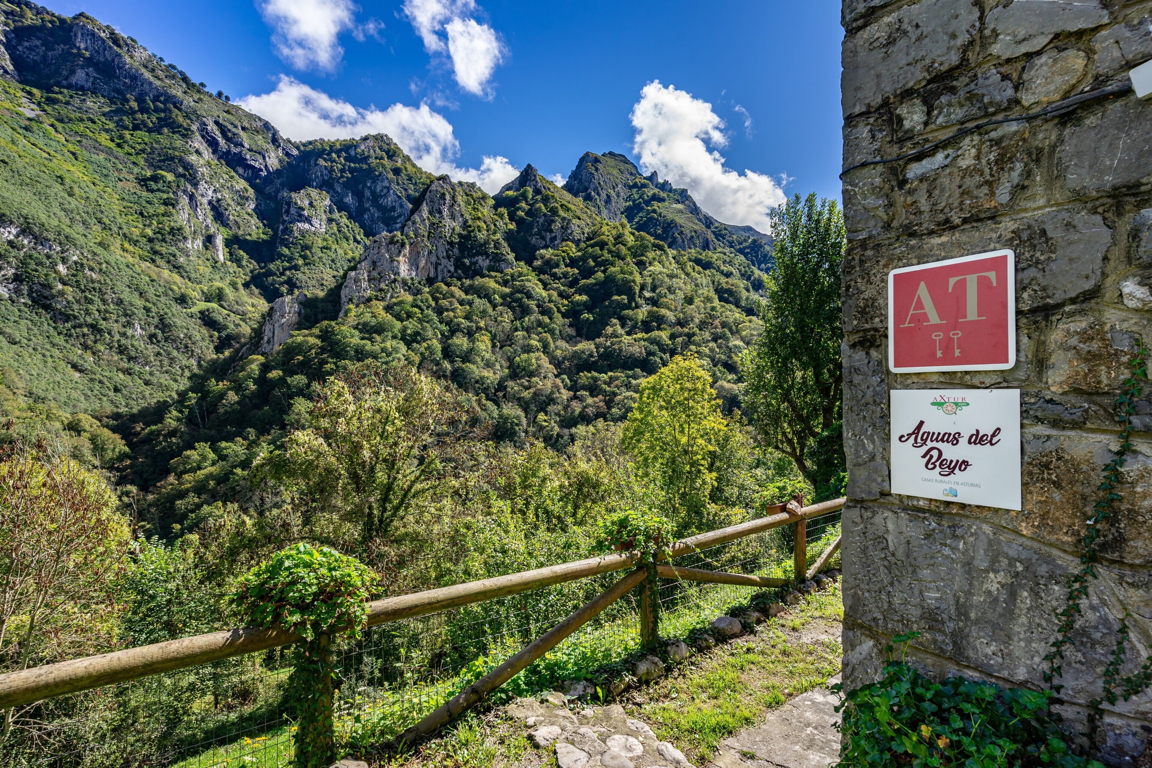 Un muro de piedra con un cartel que dice 'Aguas del Beo' y una valla de madera.