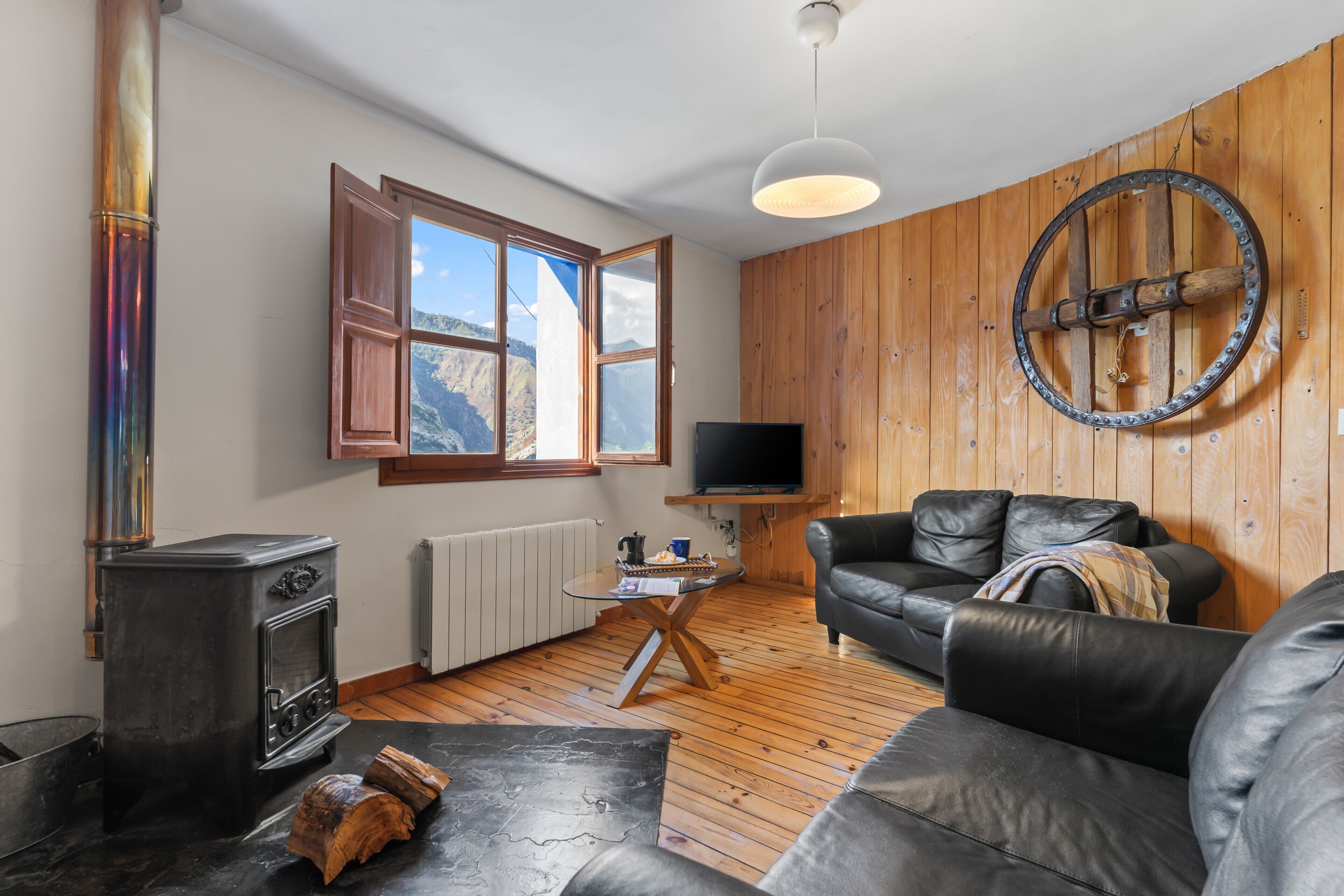 Una sala de estar con chimenea, un sofá, un televisor y una pared de madera.