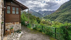 A stone building with a wooden balcony overlooking a mountainous valley. - El Rincón del Sol: Retreat and Rest in the Picos de Europa. (Cazo)