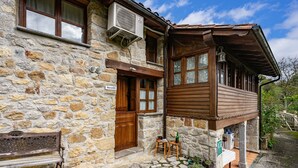 A stone building with a wooden extension, a bench, and outdoor seating. - El Rincón del Sol: Retreat and Rest in the Picos de Europa. (Cazo)
