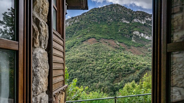 A mountain view through a window with stone walls and a wooden window frame. - El Rincón del Sol: Retreat and Rest in the Picos de Europa. (Cazo)