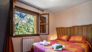 Een slaapkamer met een groot raam, een bed met een kleurrijke sprei en een radiator.
