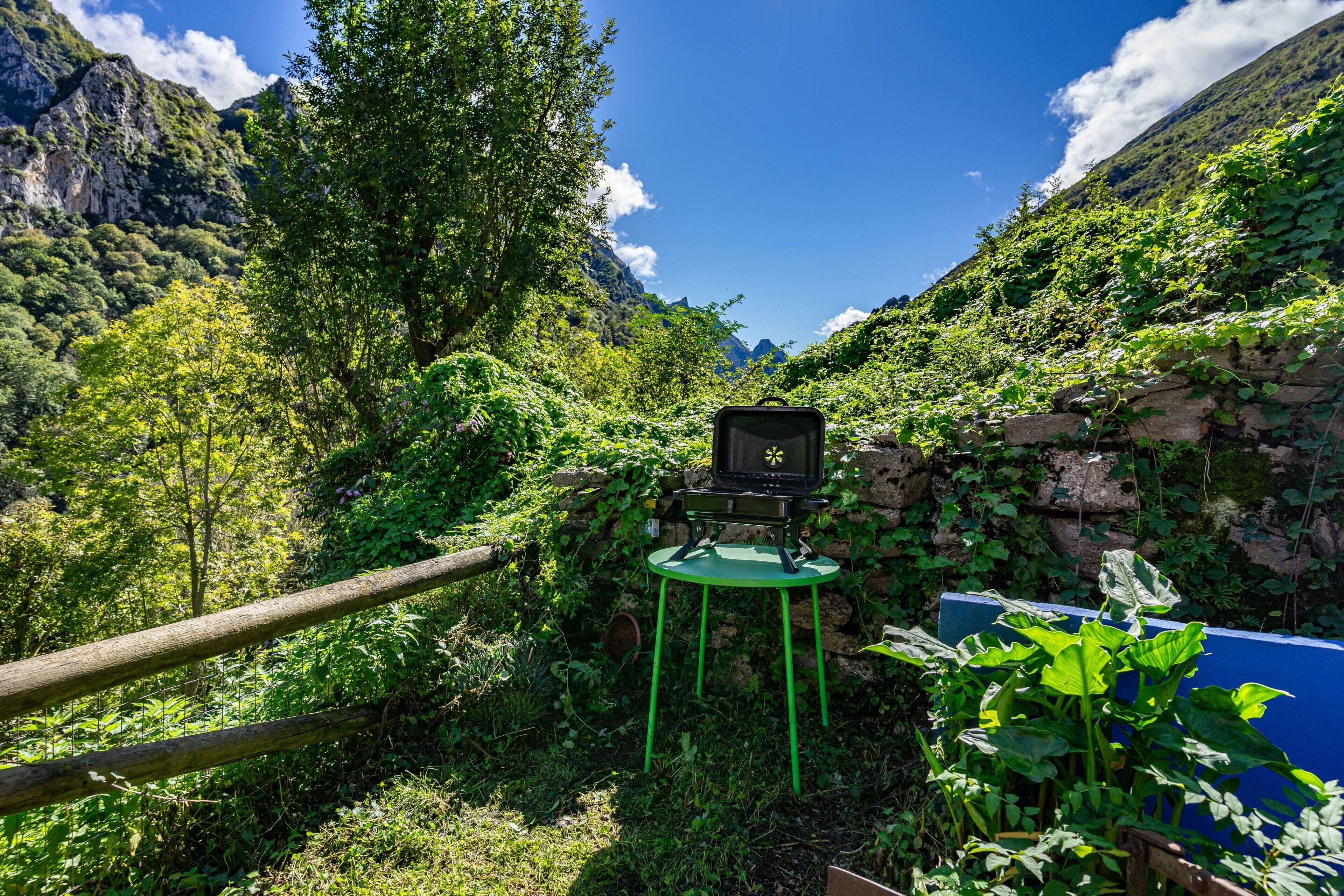 A green chair and table set against a mountainous backdrop.
