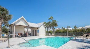A pool area with a covered seating area, a pool ladder, and lounge chairs.