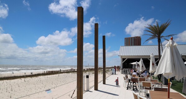 A beachside patio with tables and chairs, overlooking the ocean.