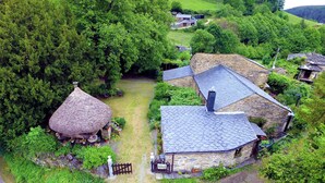 A rural setting with stone buildings, a thatched-roof structure, and lush greenery. - Casa Rural 'Nogueira' with Mountain Views, Private Terrace, and Wi-Fi (A Fonsagrada)
