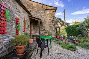 A stone building with a patio area, a table, and chairs.