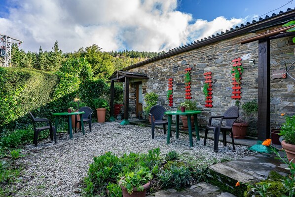 A stone building with a gravel patio, outdoor seating, and potted plants.