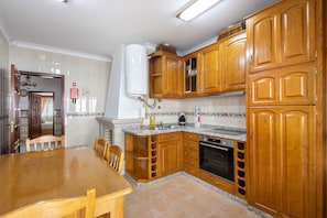 A kitchen with wooden cabinets, a granite countertop, a built-in oven, and a dining table with chairs.