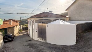 Un bâtiment avec un toit recouvert de tuiles, une façade blanche et une porte portant une plaque avec un numéro.