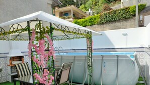Un espace extérieur abrité comprenant une piscine, un barbecue et une prise de courant.
