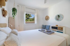 Une chambre à coucher avec un lit, une fenêtre, une table de chevet et un miroir fixé au mur.