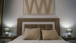 A neatly made bed with two pillows, a wooden headboard, and two bedside lamps on nightstands.