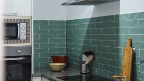 A kitchen with a microwave, oven, stove, and a stainless steel range hood.