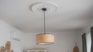 A living room with a sofa, a cabinet, a television, and a hanging light fixture.