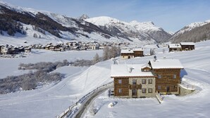 A snow-covered mountain village with wooden houses, a ski slope, and a clear sky. - Chalet 'Rain Villa Genf' with Mountain View, Shared Garden and Wi-Fi (Livigno)