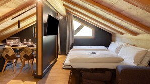 A room with a bed, a desk with a computer, and a TV on the wall. - Chalet 'Rain Villa Genf' with Mountain View, Shared Garden and Wi-Fi (Livigno)