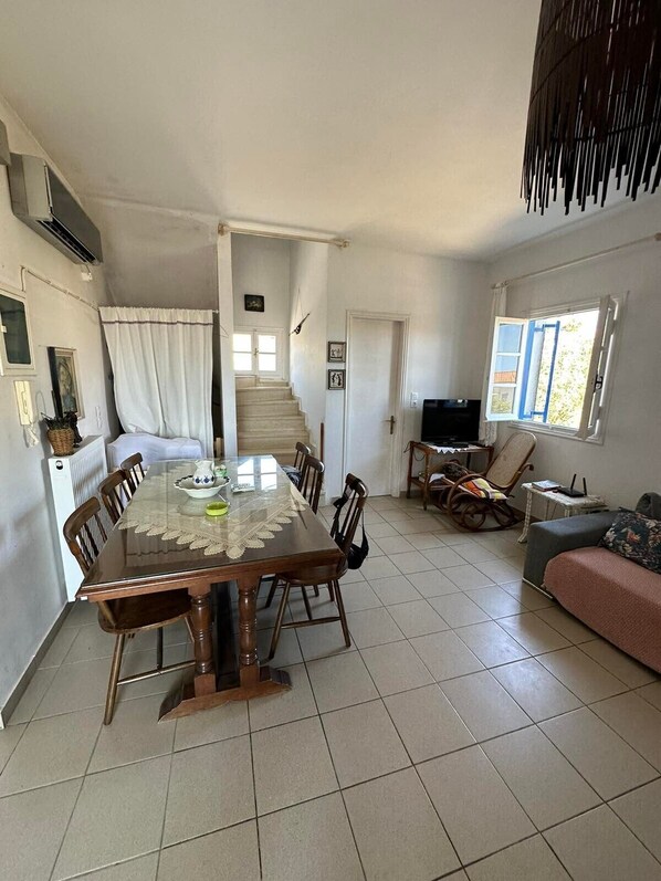 Un espace repas comprenant une table, des chaises et un escalier menant à une autre pièce.