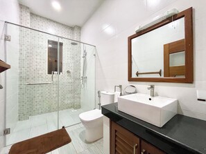 A bathroom with a glass-enclosed shower, a white sink, and a wooden cabinet.
