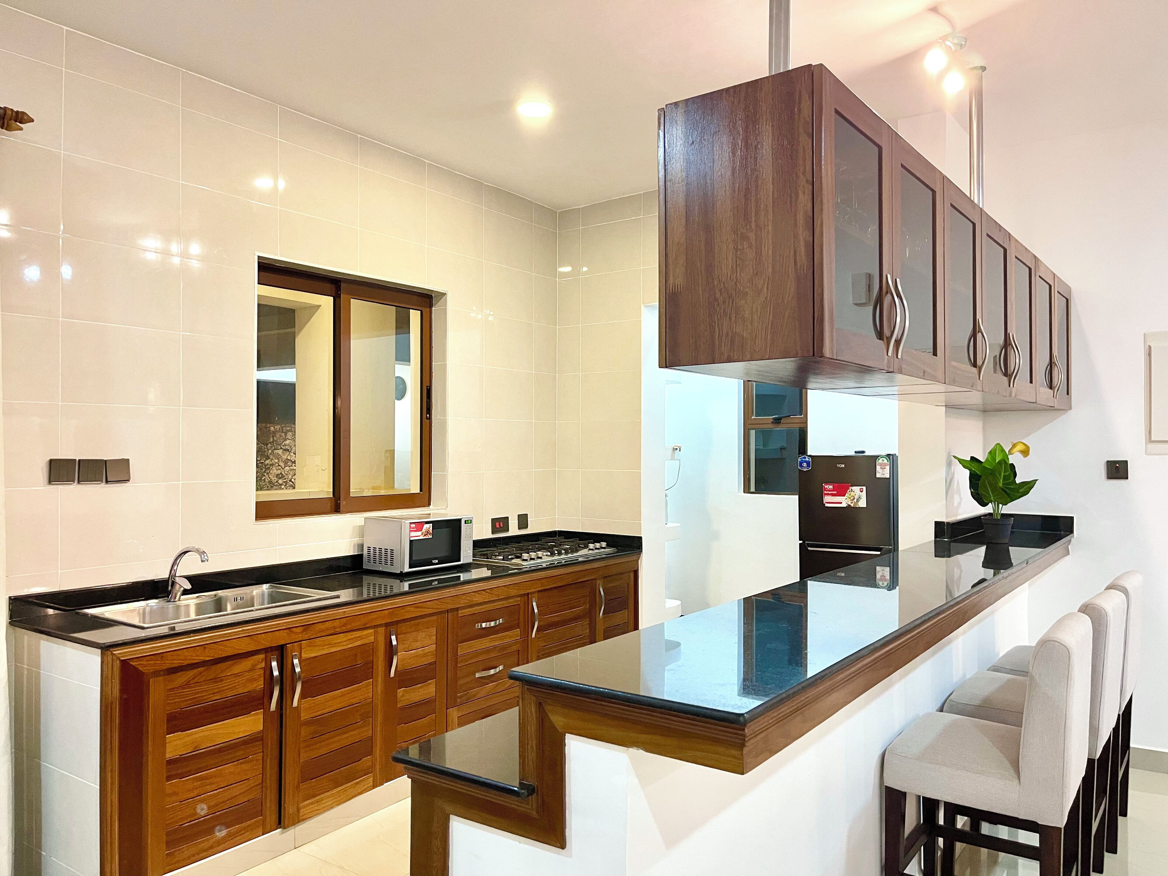 Una cocina moderna con armarios de madera, un lavamanos de acero inoxidable y una encimera negra.