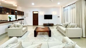 A modern living room with two sofas, a coffee table, a TV, and a ceiling fan. - Pazuri at Vipingo  (Kibaoni)