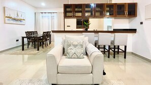 A modern living room with a sofa, dining table, chairs, and a kitchen area with cabinets and a countertop. - Pazuri at Vipingo  (Kibaoni)