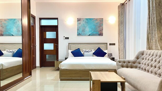 A hotel room with two beds, a sofa, a wooden coffee table, and artwork on the walls. - Pazuri at Vipingo  (Kibaoni)