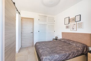 Quarto com cama, guarda-roupa, mesa de cabeceira e quadros nas paredes.