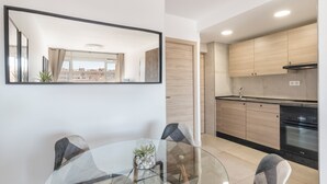 Una cocina moderna con armarios de madera, horno empotrado y una mesa de comedor de vidrio con sillas.