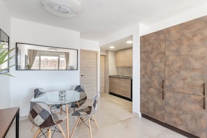 Cozinha moderna com área de refeições, com uma mesa de vidro, cadeiras e um armário grande.