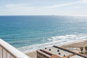 Um hotel à beira-mar com terraço no terraço com vista para o mar, uma praia de areia e céu claro.