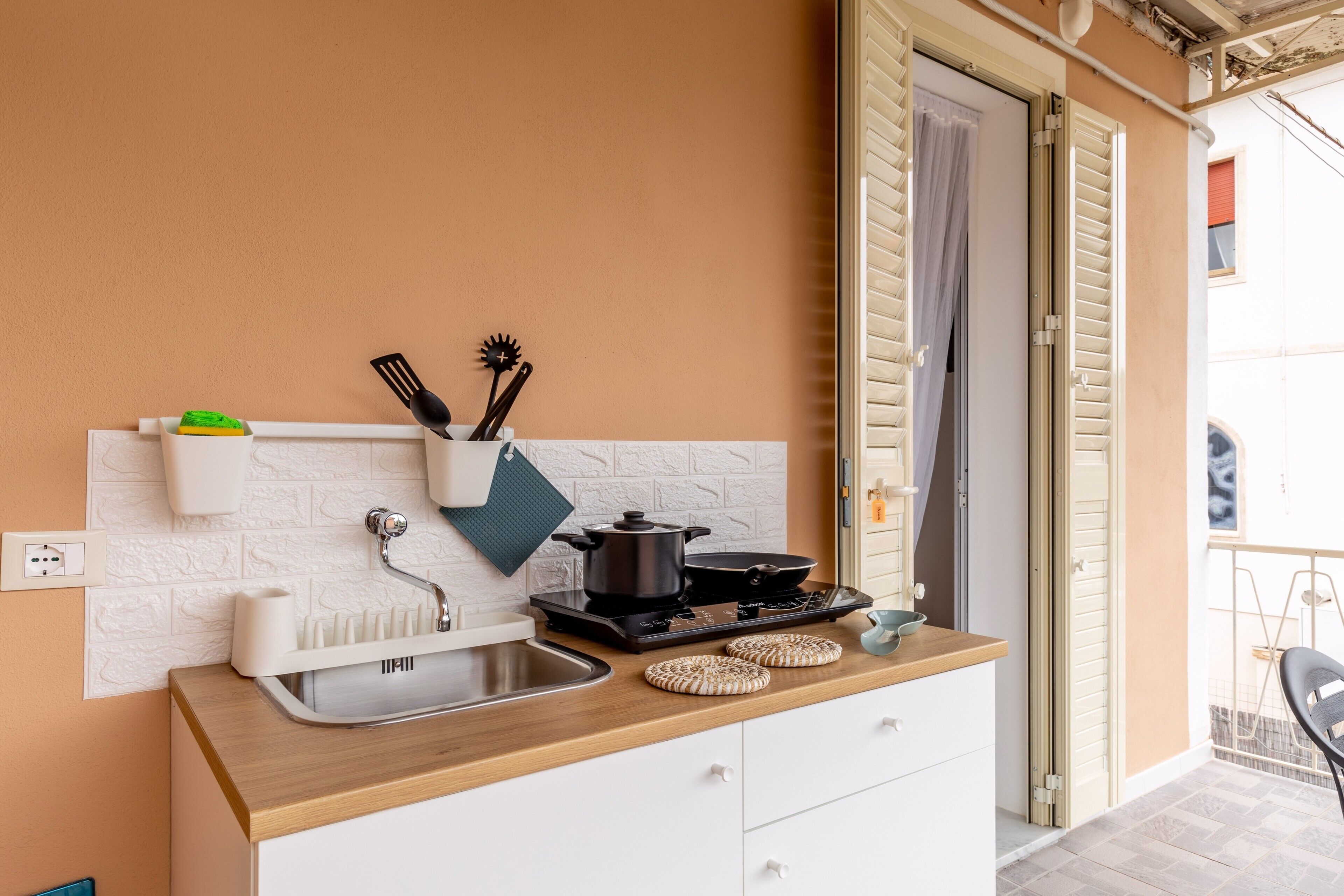 Una cucina compatta con lavello, fornelli e mobili bianchi.