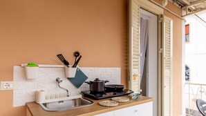 Cocina compacta con fregadero, estufa y armarios blancos.