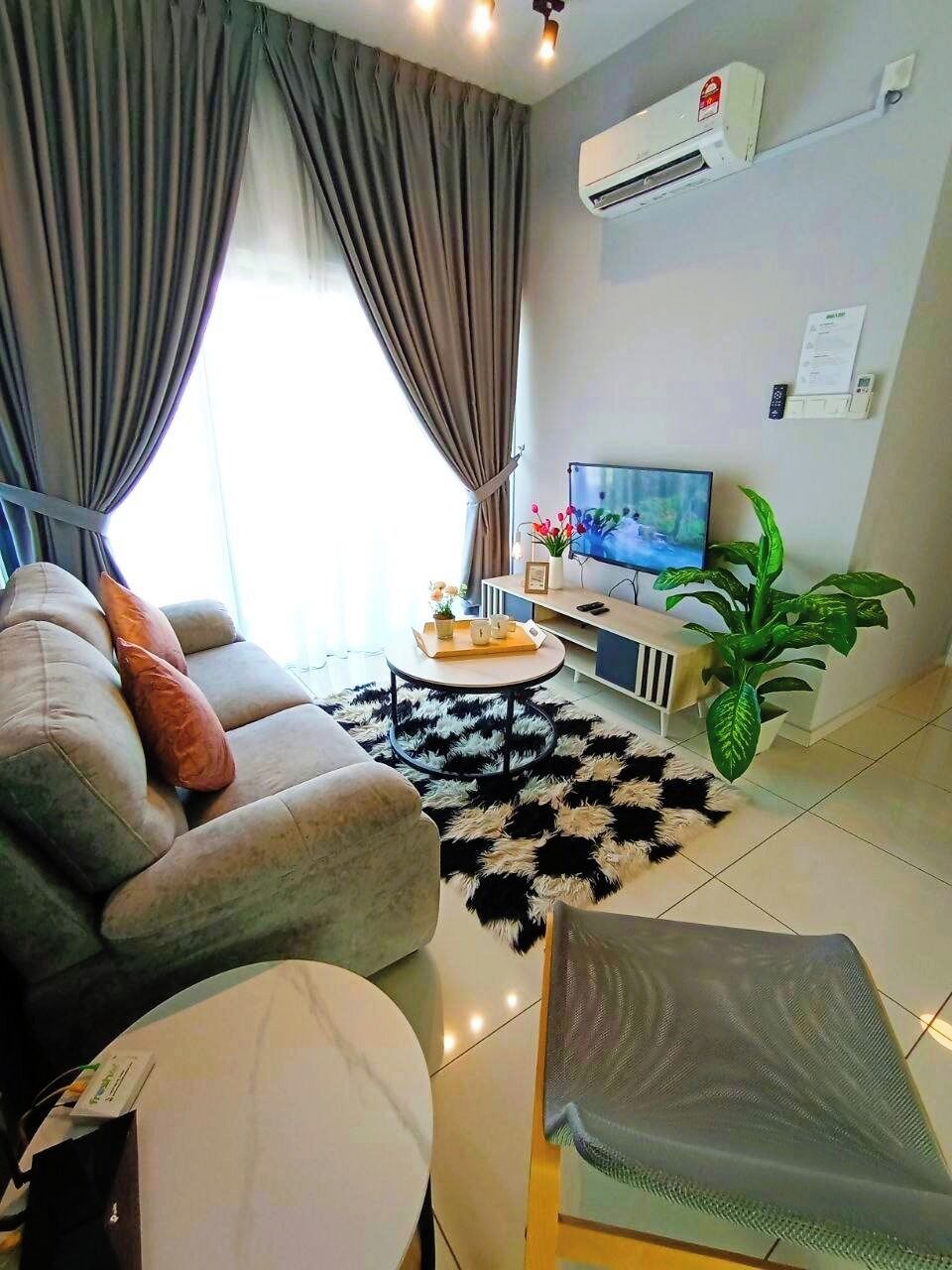 A modern living room with a sofa, a coffee table, a TV, and an air conditioner.