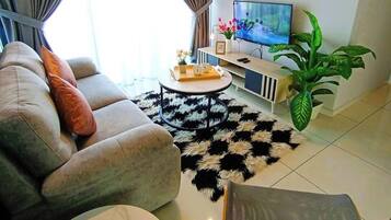 A modern living room with a sofa, a coffee table, a TV, and an air conditioner.