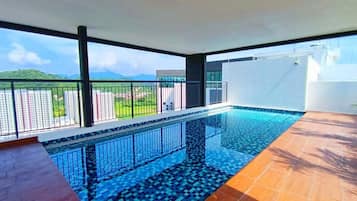 Ein moderner Innenpool mit freiem Blick auf die Umgebung, darunter ein Balkon und entfernte Gebäude.