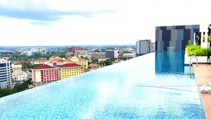 Una piscina infinita en la azotea con vista a la ciudad, arquitectura moderna y cielo despejado.