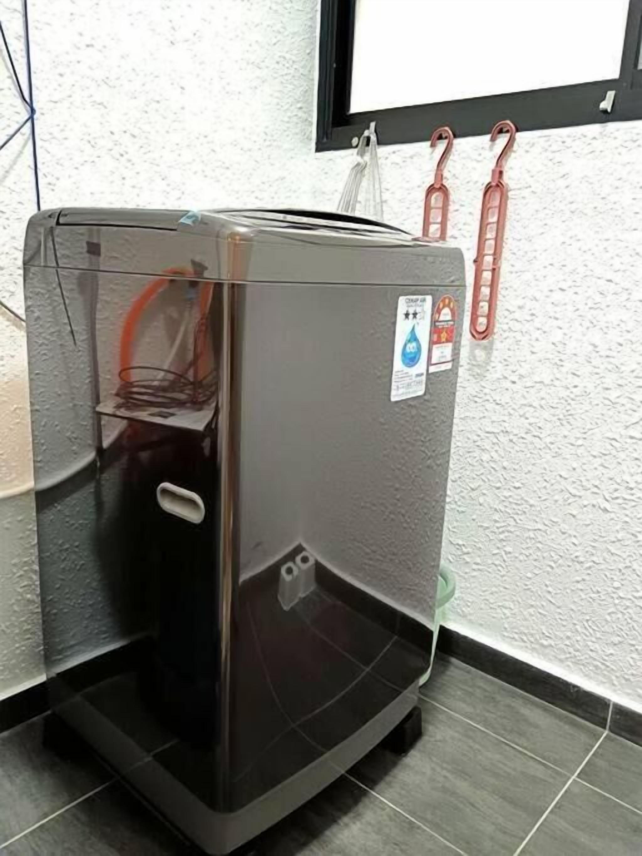 A compact, gray water dispenser with a clear water bottle holder, a water drop sticker, and a small control panel.
